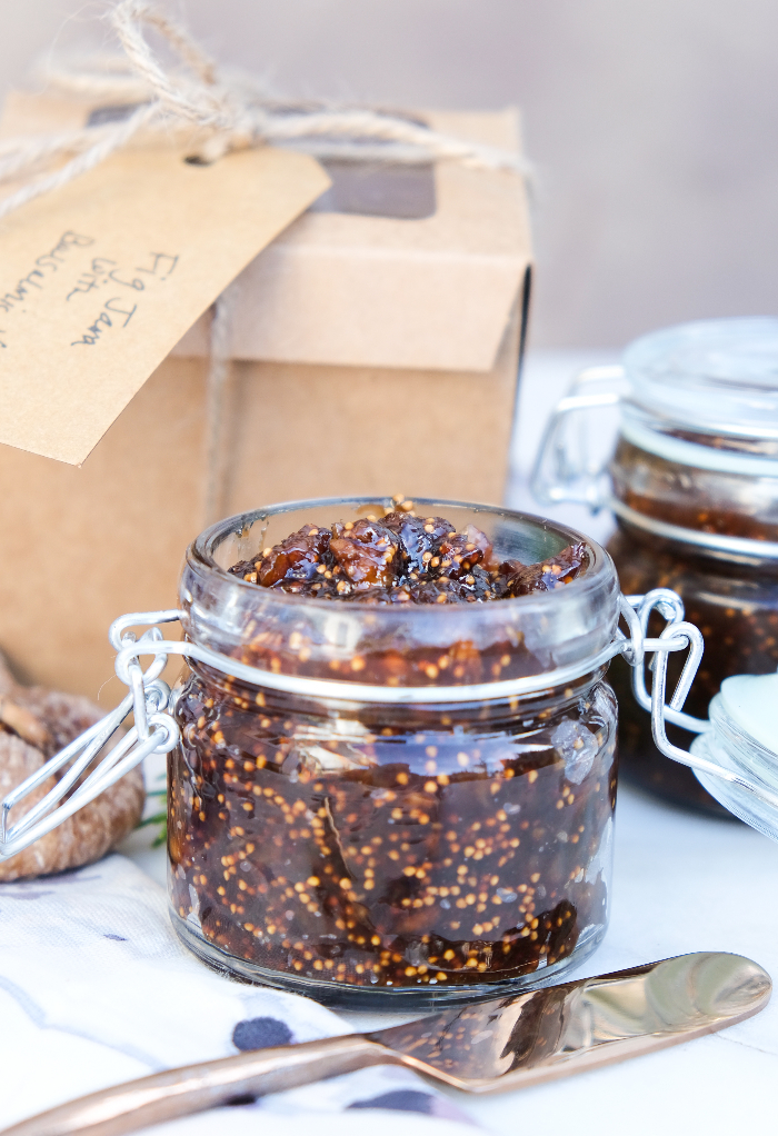 Homemade fig chutney in a clear jar with a tan box in the background. 