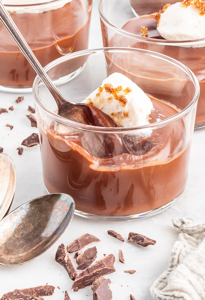 Gluten free chocolate pudding in a clear glass dessert dish ready to eat. 