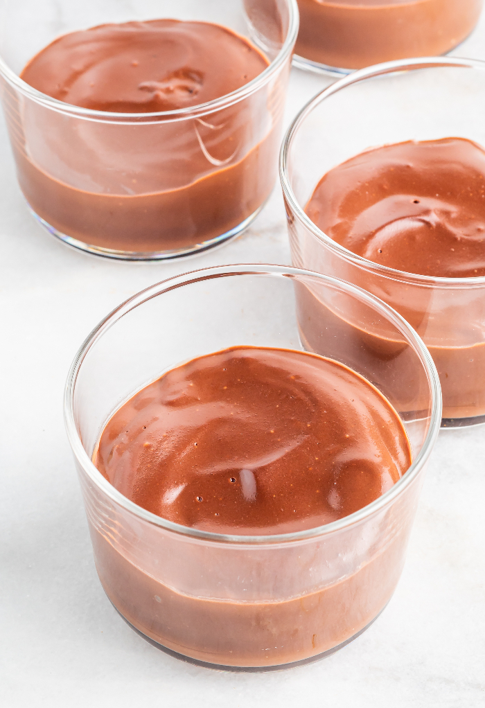 Cooked chocolate pudding in clear dessert dishes before adding whipped cream. 