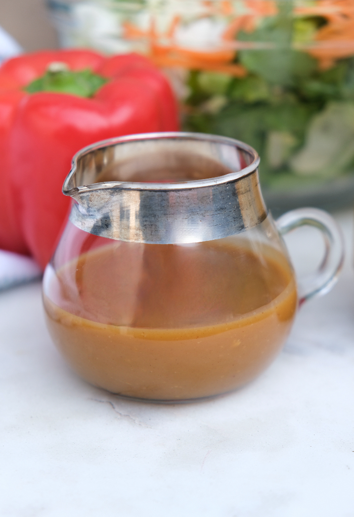 Peanut dressing in a small clear decanter for salad. 