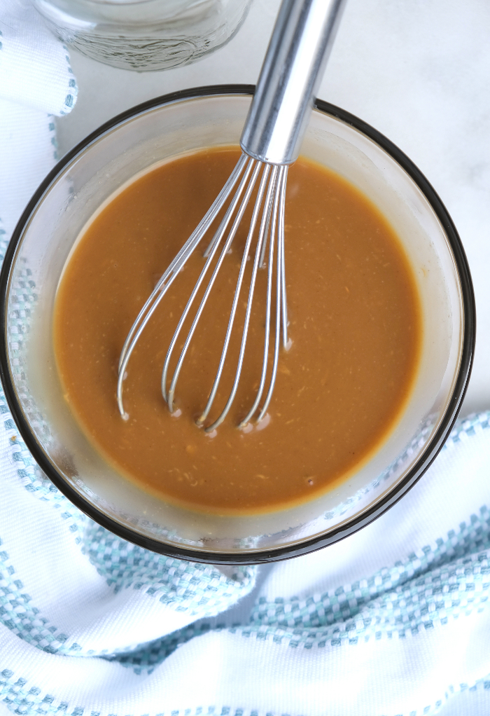 Peanut salad dressing whisked in a clear mixing bowl. 
