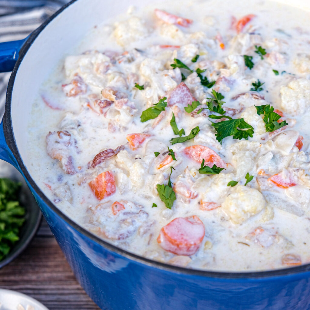 Keto clam chowder recipe cooked and simmering in a blue Dutch oven.