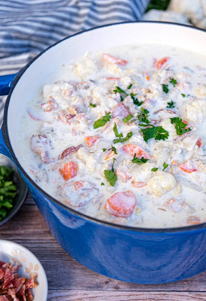 Blue dutch oven filled with clam chowder ready to serve. 