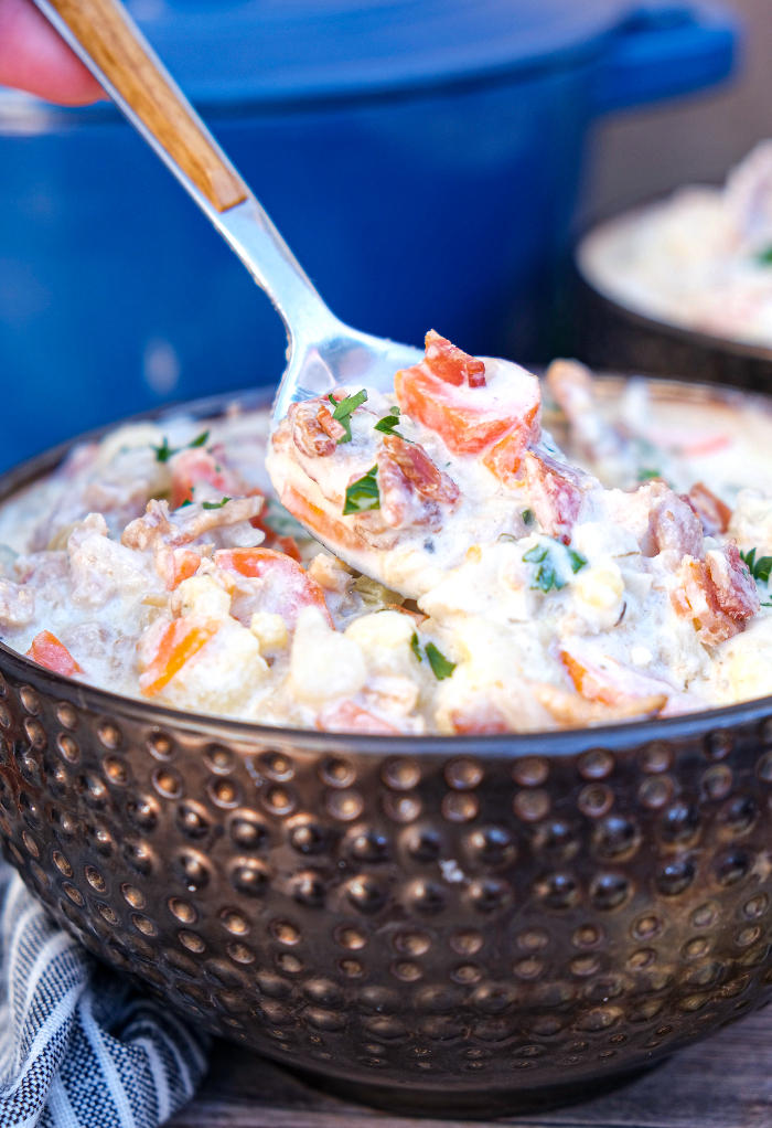 Keto clam chowder in a brown bowl with a spoon ready to eat. 