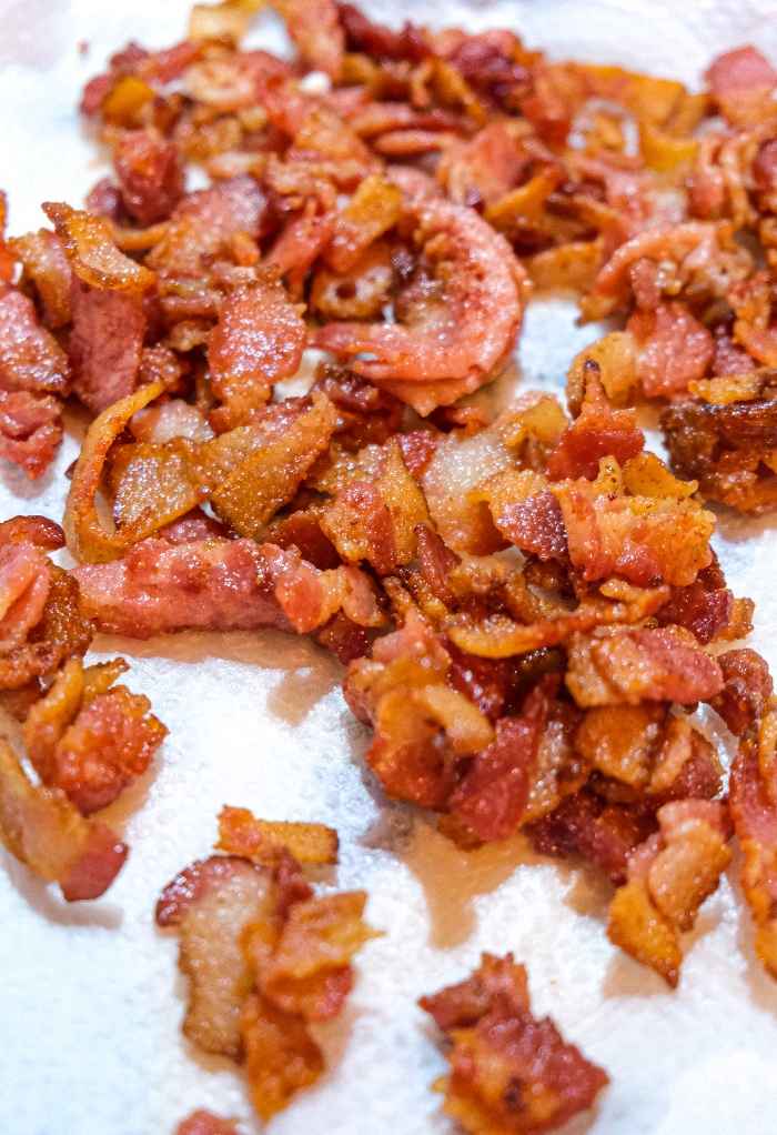 Cooked diced bacon draining on paper towels. 