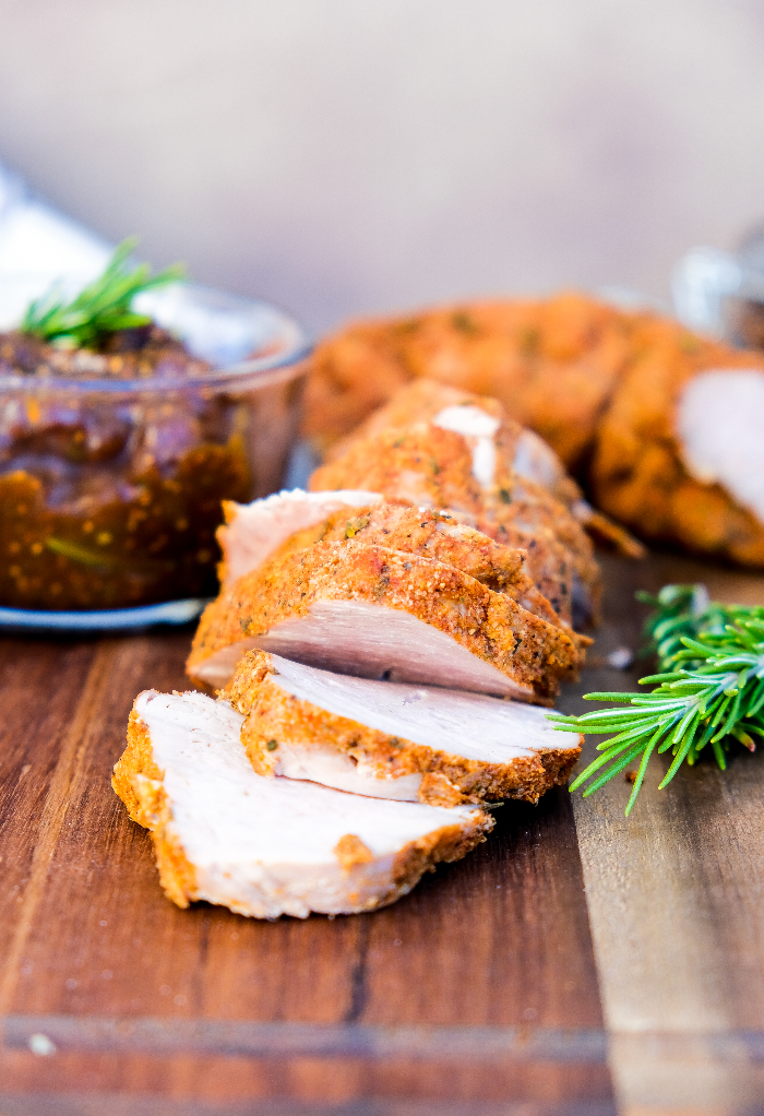 sliced pork on a cutting board with fresh rosemary on the side. 