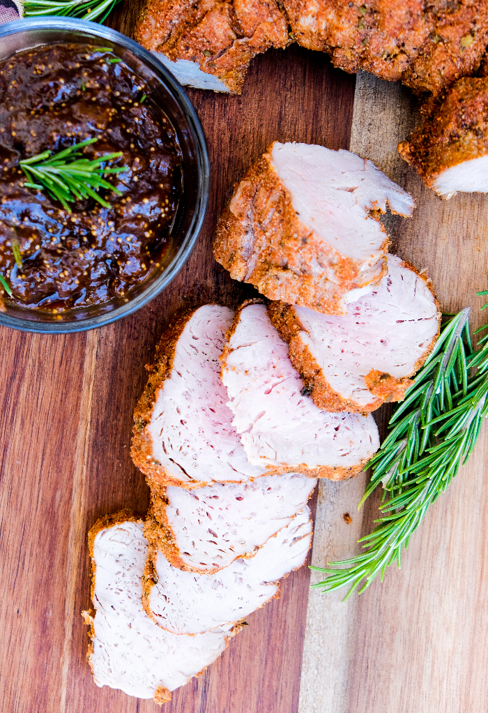 Sliced pork tenderloin on a brown wooden cutting board. 