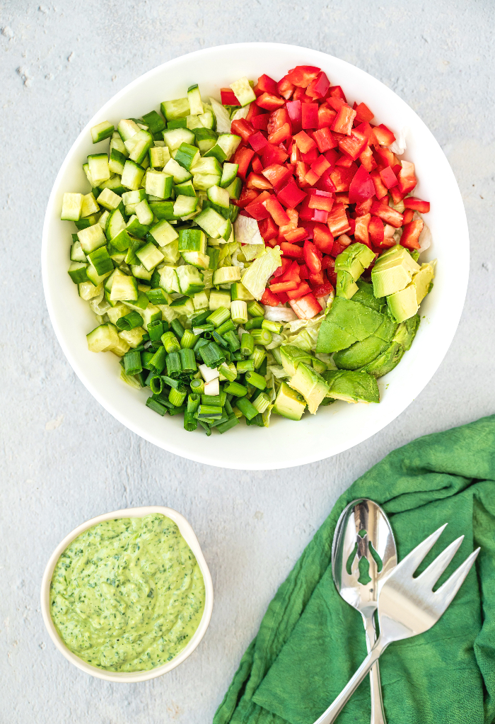 Chopped ingredients for green goddess salad with dressing on the side. 