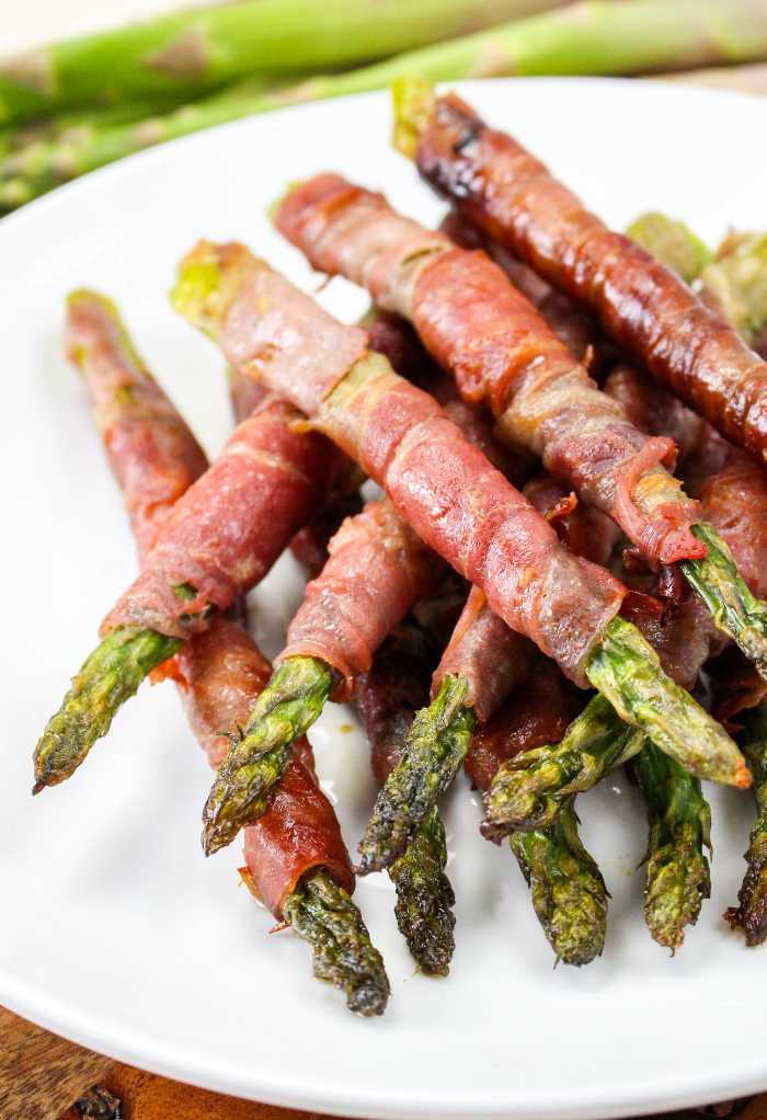 Asparagus wrapped in prosciutto on a serving dish ready to be served. 