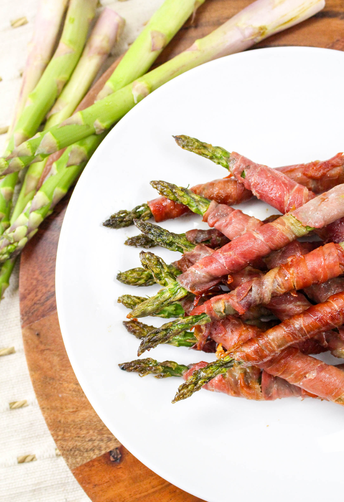 Top view of prosciutto wrapped asparagus on a serving plate ready to eat. 