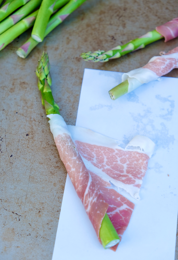 Wrapping an asparagus with prosciutto.