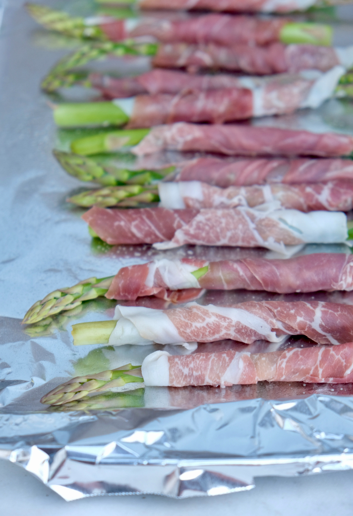 Baking sheet of asparagus wrapped in prosciutto before cooking. 