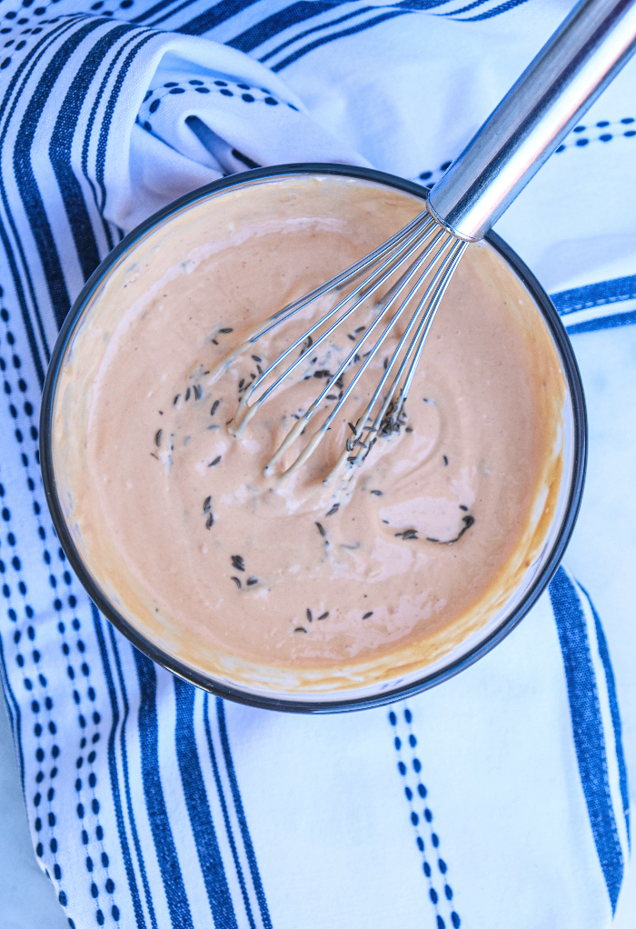 Thousand Island dressing and mayonnaise in a clear mixing bowl. 