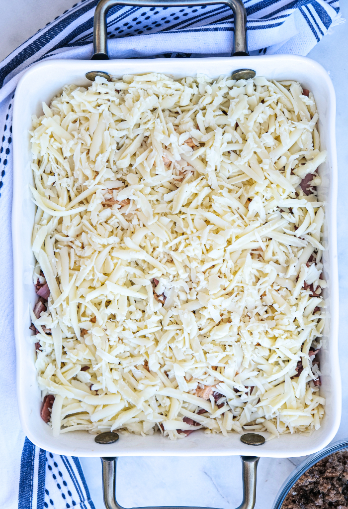 Shredded cheese over casserole in a white baking dish. 