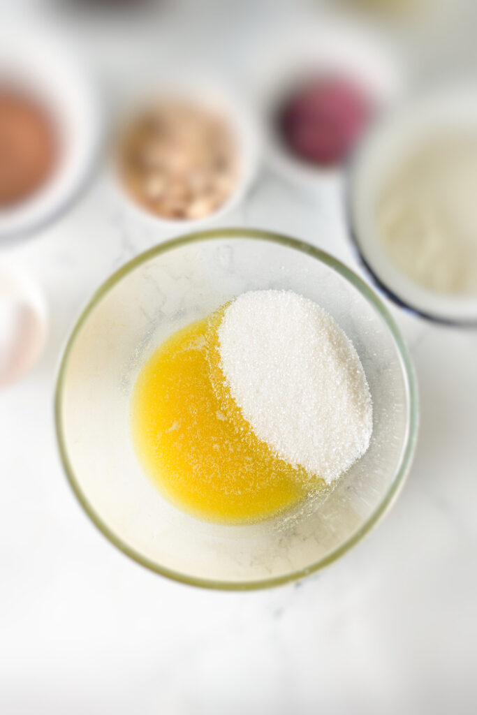 Sugar and butter in a clear mixing bowl for brownie recipe.