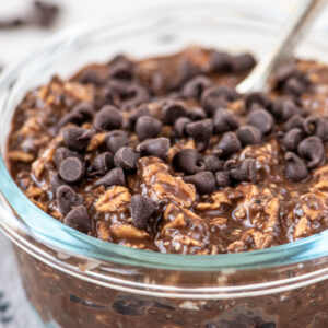 Overnight oats made with chocolate in a glass bowl topped with mini chocolate chips.