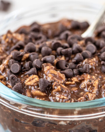 Overnight oats made with chocolate in a glass bowl topped with mini chocolate chips.