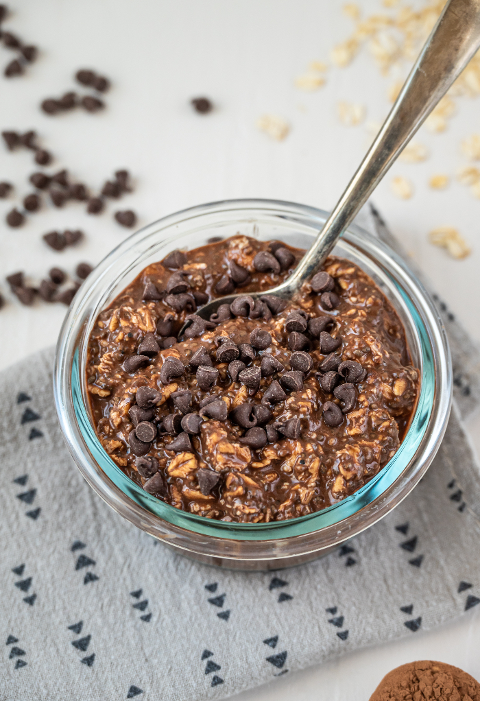 Chocolate oatmeal topped with chocolate chips in a glass bowl. 
