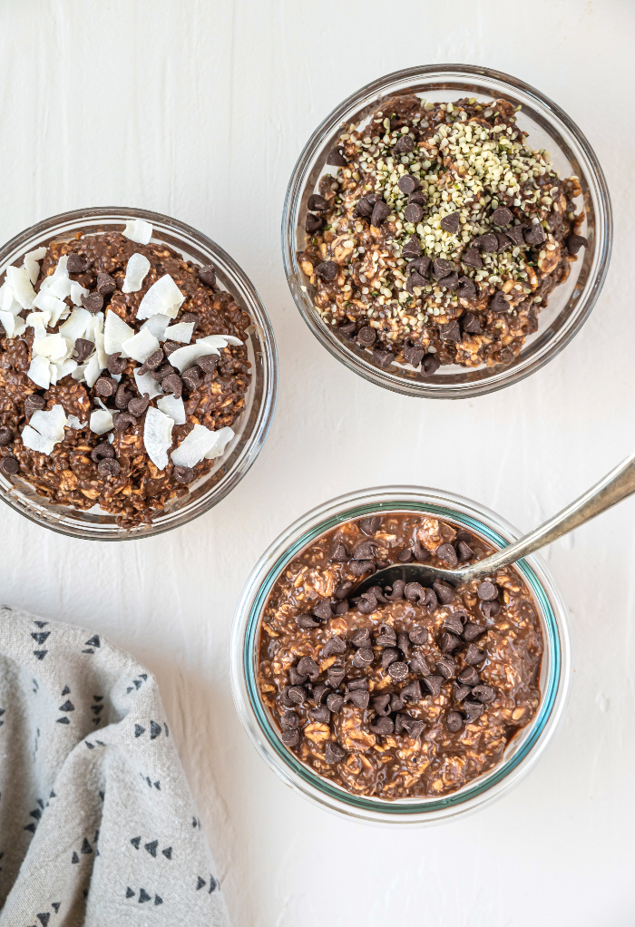 Three different small clear bowls filled with chocolate oats ready to eat. 