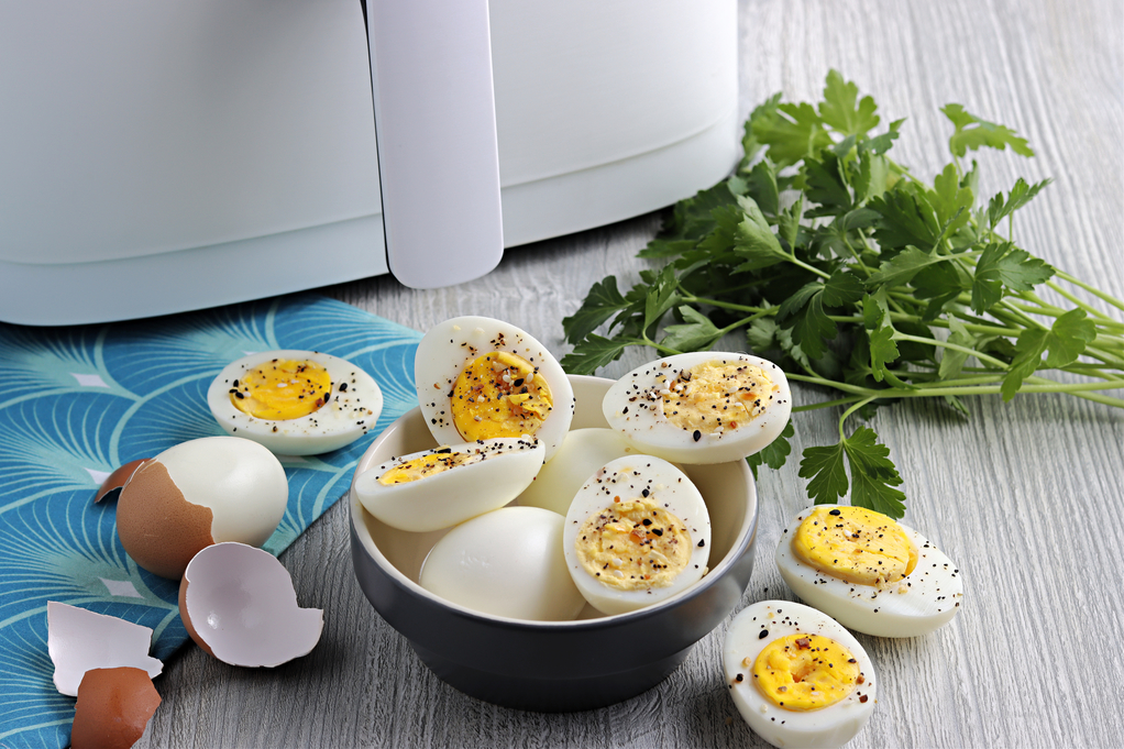 Hard boiled eggs with a white air fryer in the background. 
