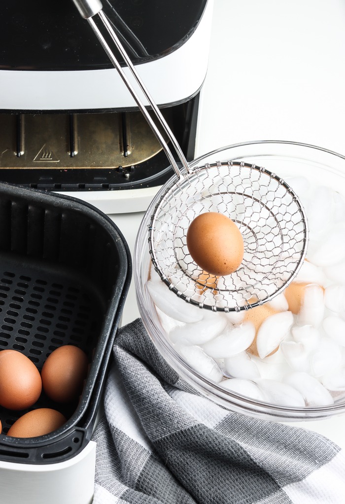 Placing cooked eggs in an ice bath before peeling.