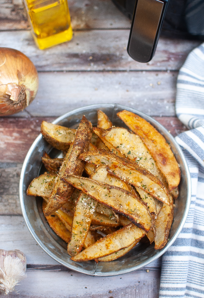 Homemade potato wedges in a light blue bowl cooked in an air fryer.