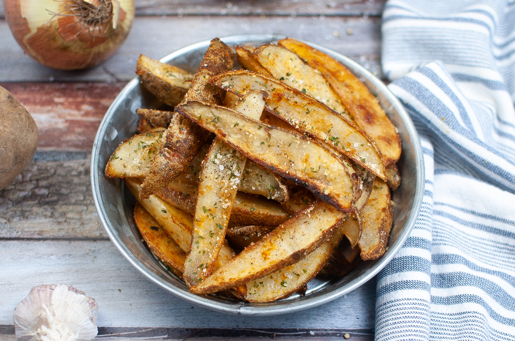 Homemade potato wedges in a blue serving dish. 