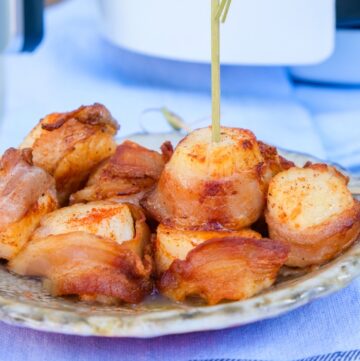 Scallops wrapped in bacon on a ceramic plate.