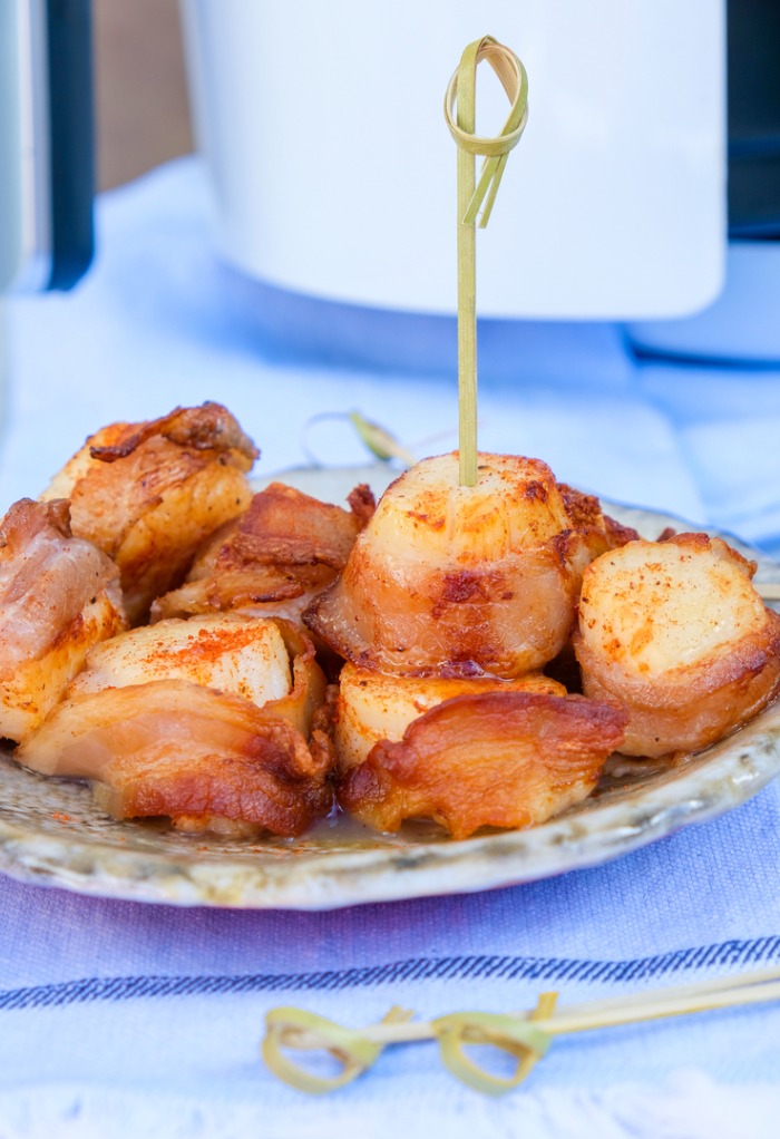 Scallops wrapped in bacon on a ceramic plate.