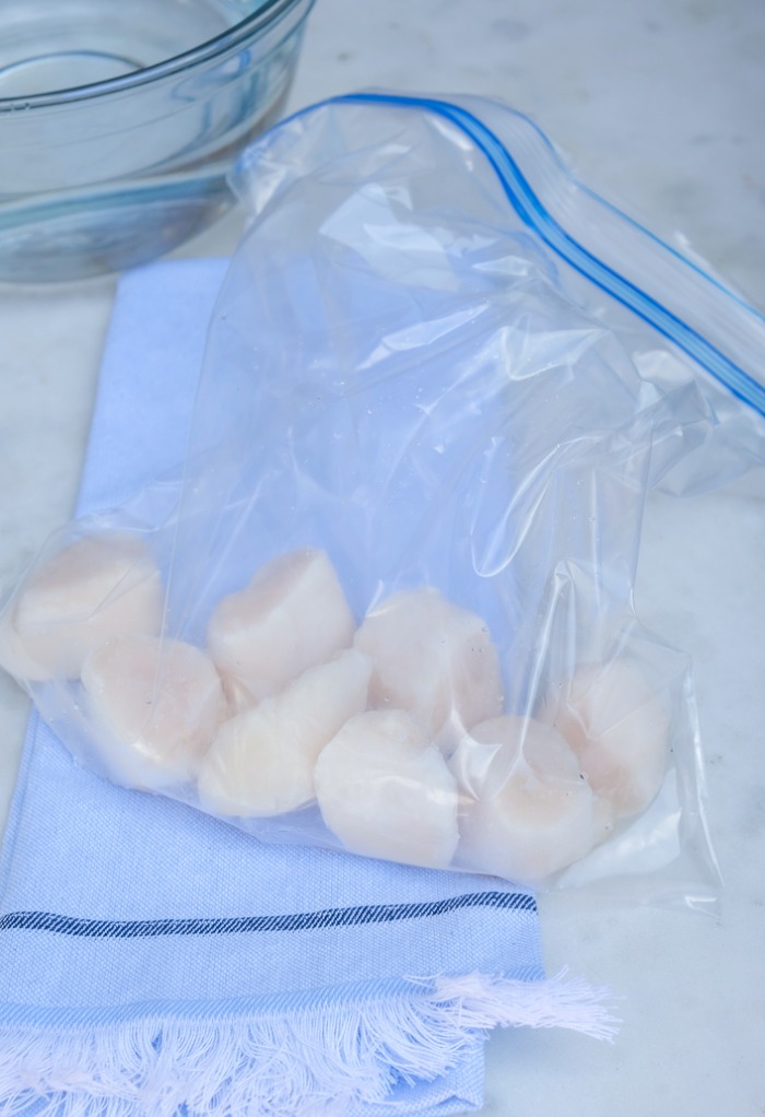 Defrost frozen scallops in a plastic bag.