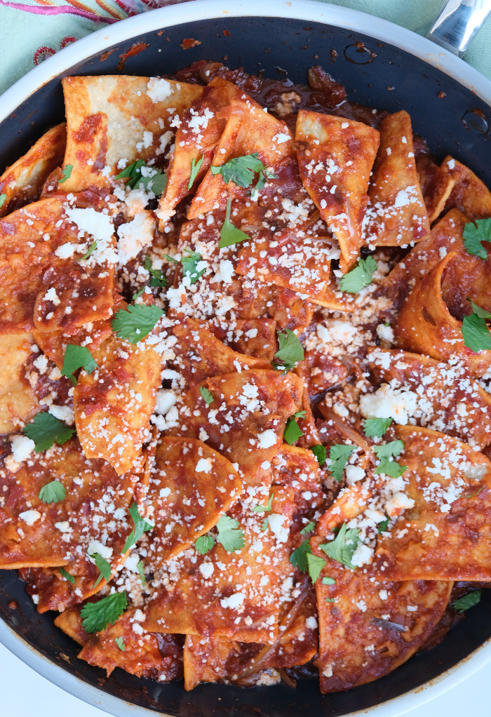 Chilaquiles cooked in a skillet topped with cheese and cilantro.