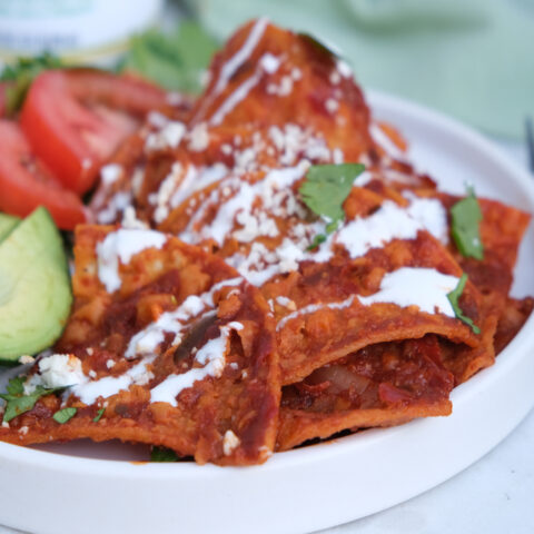 Homemade chilaquiles recipe topped with cheese and creama.