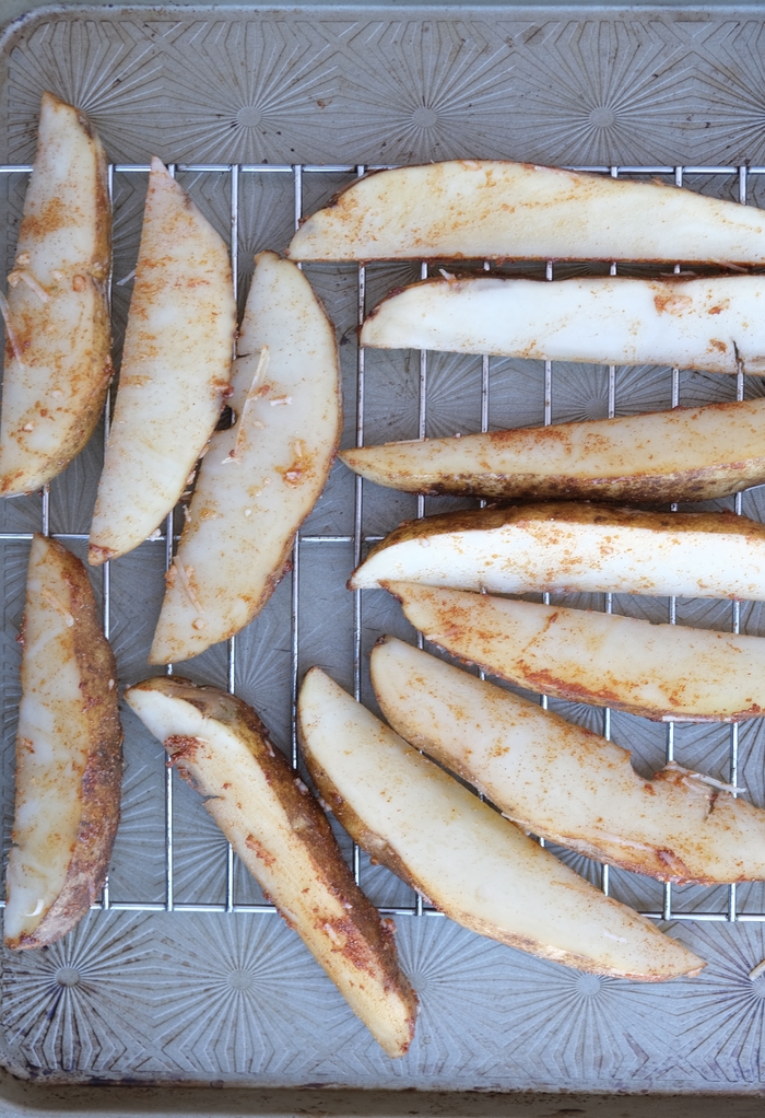 Sliced potatoes on a baking sheet ready to cook in the oven. 