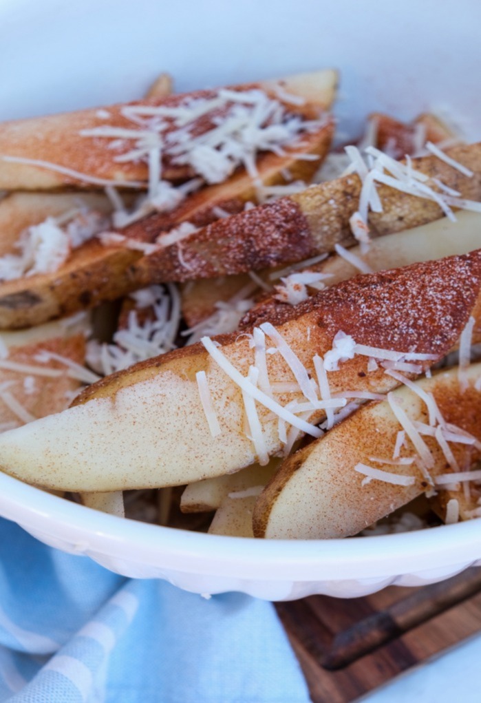 Potato wedges topped with spices ready to season for cooking. 
