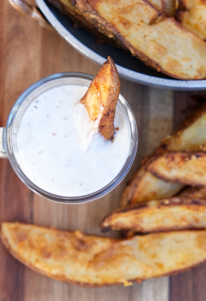 Potato wedge dipped in ranch dressing ready to eat. 