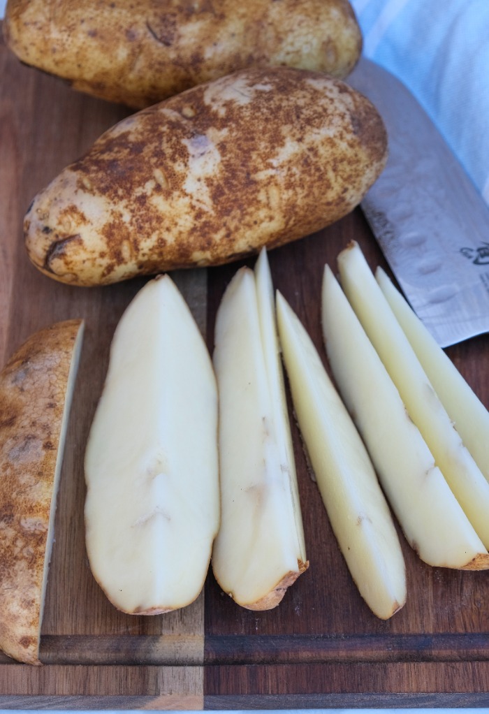 Potatoes sliced into wedges ready to season and cook.