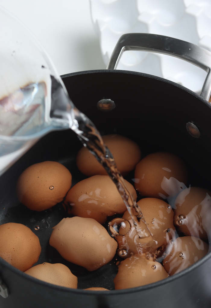 Topping eggs with water in a pot before boiling to cook on the stovetop.