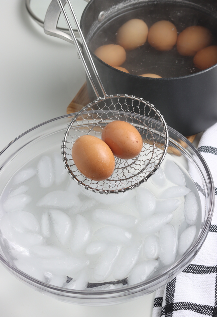 Placing eggs in a bowl of ice to stop the cooking process. 