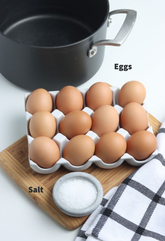 Eggs and salt with a stockpot in the back ready to cook hard boiled eggs. 