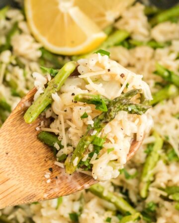 Wooden spoon of risotto and asparagus with lemon ready to plate.