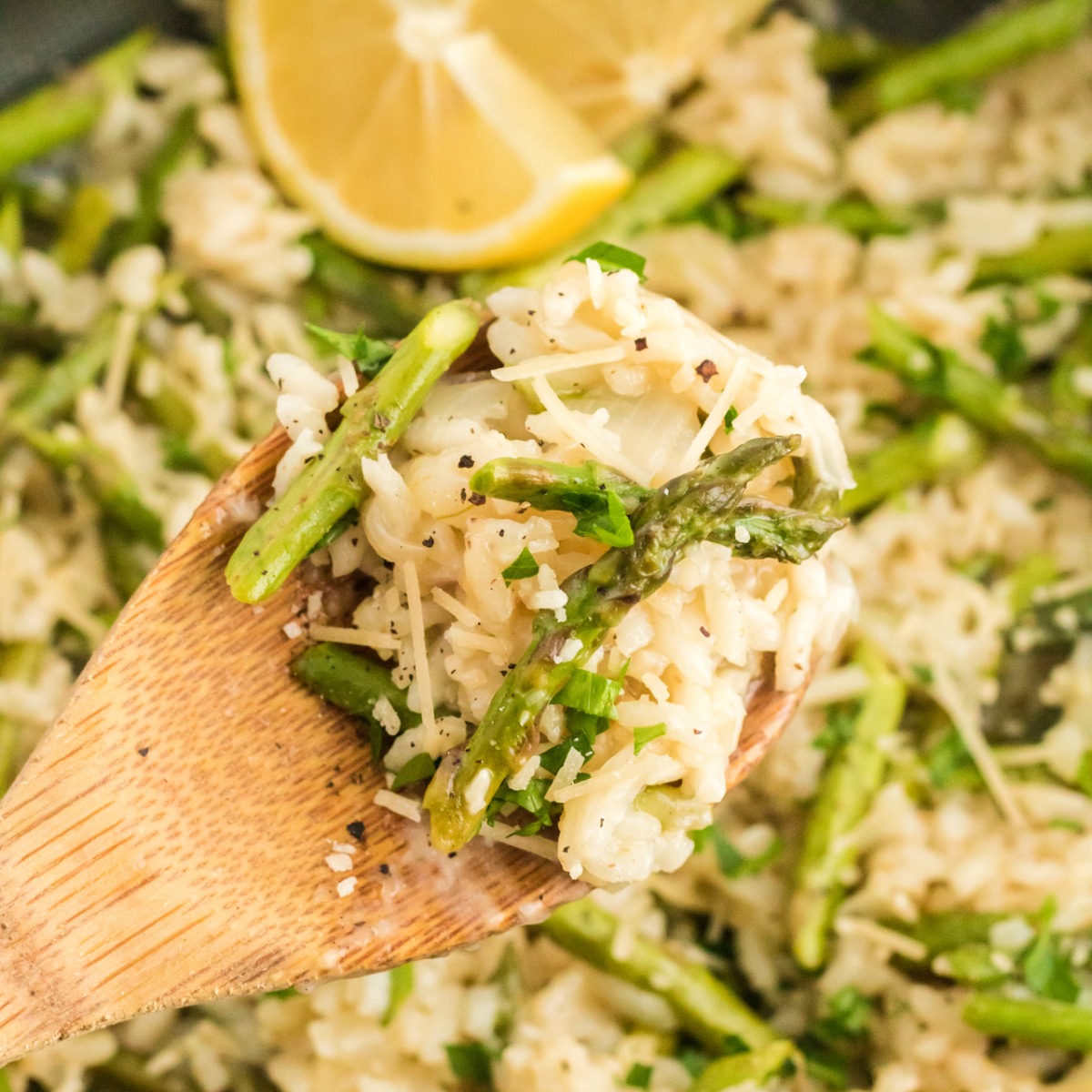 Wooden spoon of risotto and asparagus with lemon ready to plate.