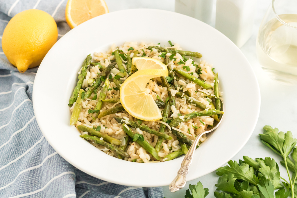 Risotto with asparagus and lemon in a white serving dish ready to eat. 