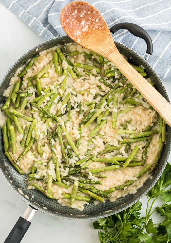 Asparagus added to the coked risotto in a skillet. 