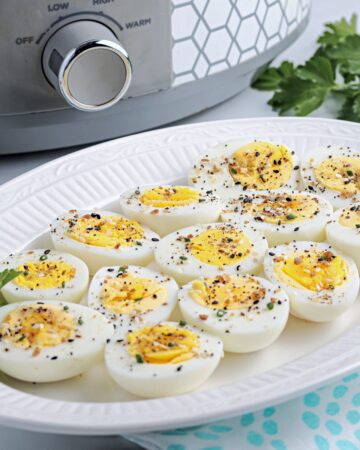 Hard boiled eggs on a white serving dish ready to eat.