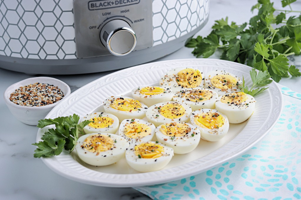 Hard boiled eggs on a plate with a slow cooker in the background. 