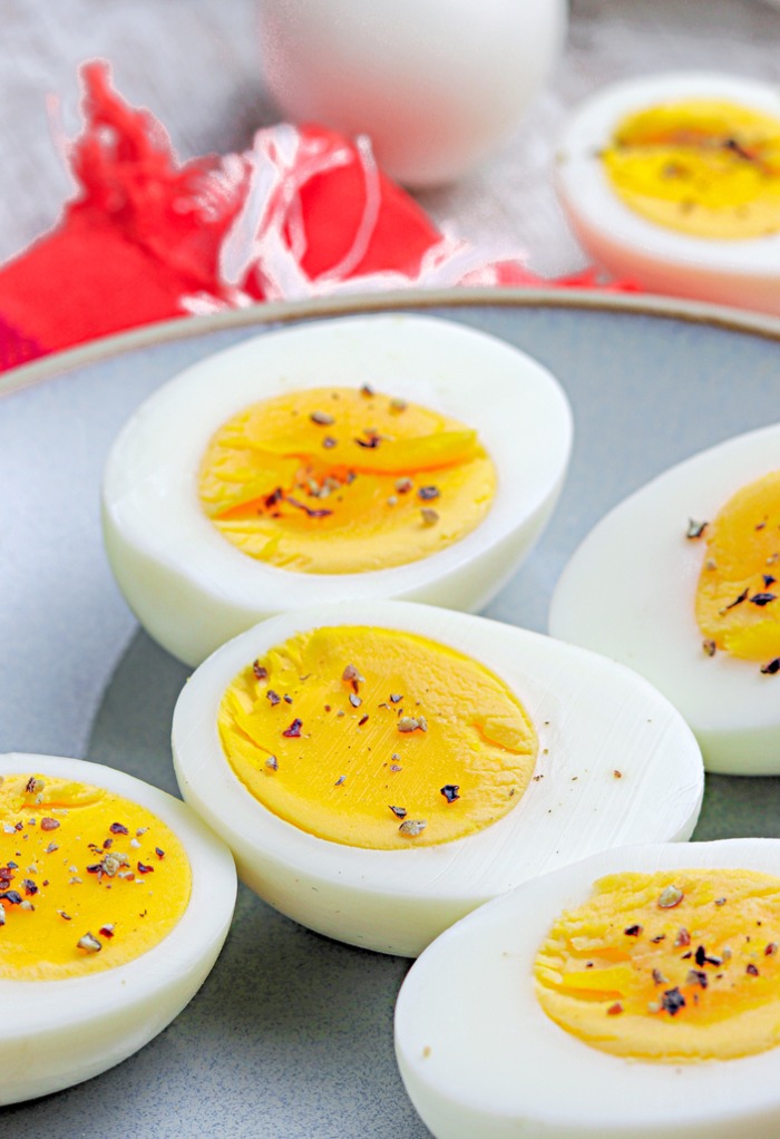 Sliced hard boiled eggs with salt and pepper on a gray plate. 