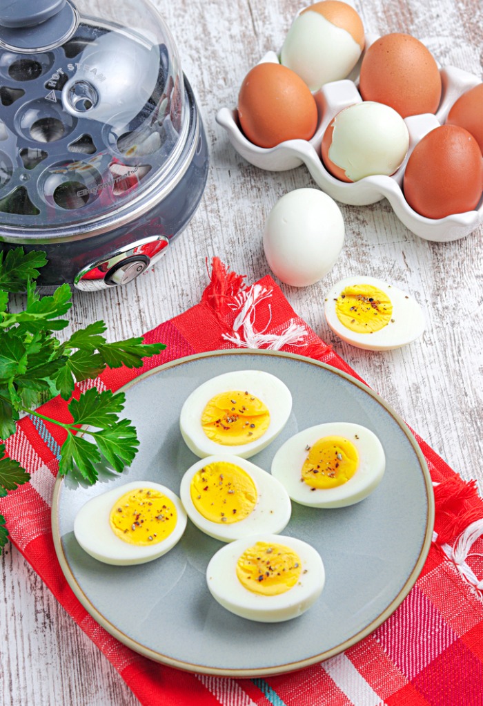 Top view of hard boiled eggs with an egg cooker on the side. 