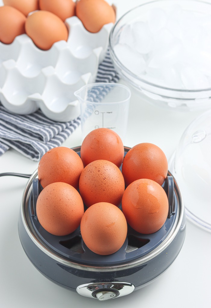 Adding eggs to egg cooker to cook. 