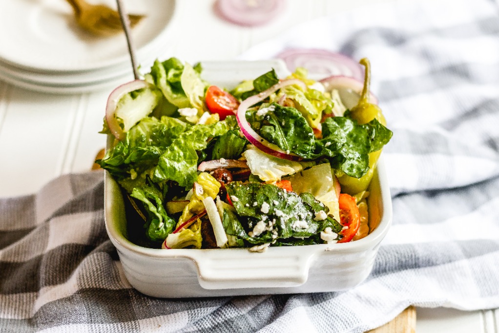 Greek salad in a white serving dish ready to eat. 