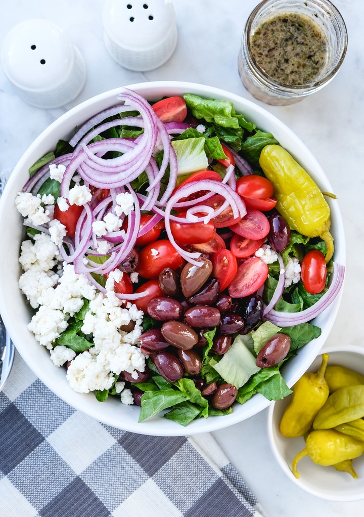 Top view of Greek salad in a white serving bowl before tossing. 